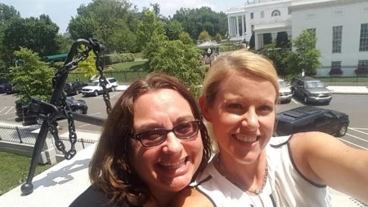 Two women smile in a selfie in front of the White House.
